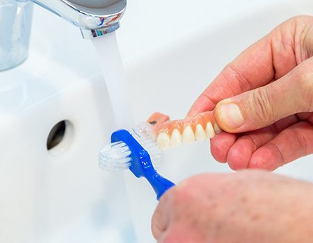 Closeup of patient brushing their dentures