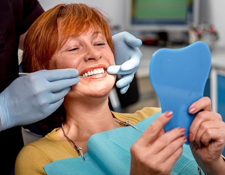 Woman smiling at reflection in dentist's office