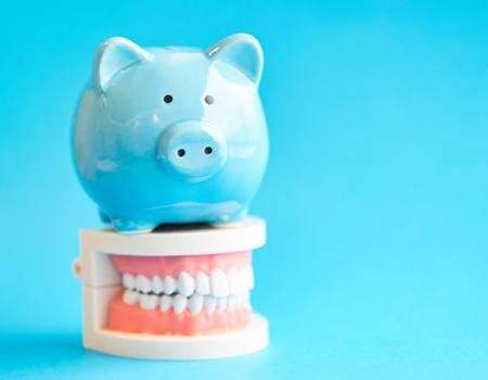 light blue piggy bank on top of a set of dentures 