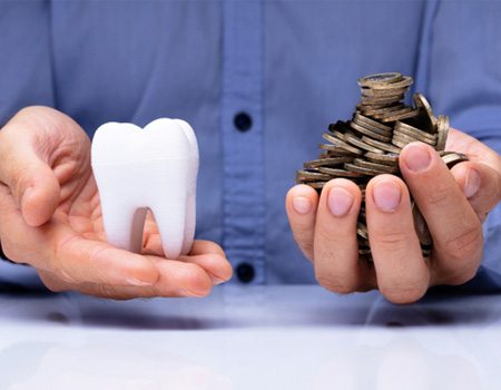 Man weighting giant tooth and coins in his hands 