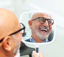 Man with black glasses smiling in mirror