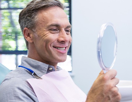 Older man looking at smile in mirror