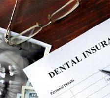 Dental insurance paperwork next to X-ray on wooden desk 