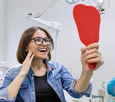 Patient holding mirror, admiring the results of her cosmetic treatment