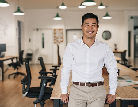 person smiling and sitting on a conference table at work