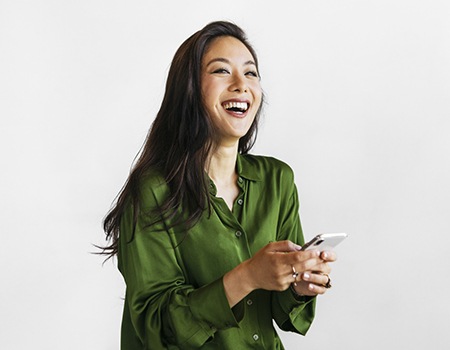 Woman in green shirt smiling while holding a phone