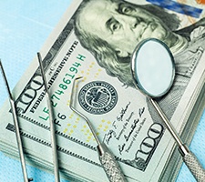 Dental instruments resting on a stack of money