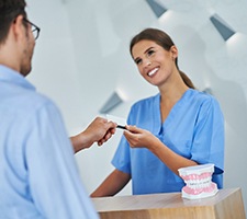 Dental assistant handing a pen to her patient