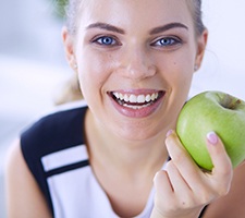 Woman smiling while holding a green apple