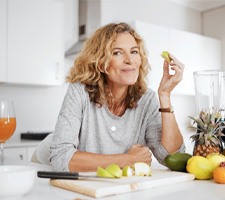 Woman smiling while eating fresh fruit at home