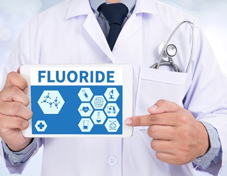Dentist pointing to a tablet that reads “Fluoride”