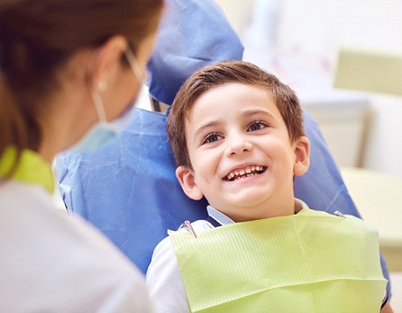 Little boy smiling at female dentist ready for fluoride treatment
