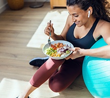 Woman leaning on an exercise ball and eating a healthy meal