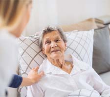 Older woman with dental implants in Azle smiling in bed