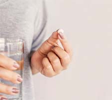 Person holding painkiller and glass of water