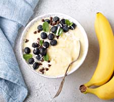 Bowl of creamy banana with blueberries and mint leaves