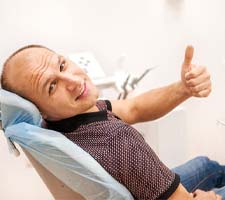 Man smiling at dental office and giving a thumbs up