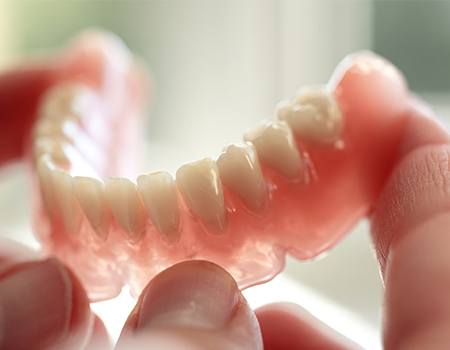 Hand holding a full denture