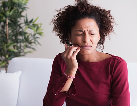 person with sensitive teeth holding their mouth in discomfort