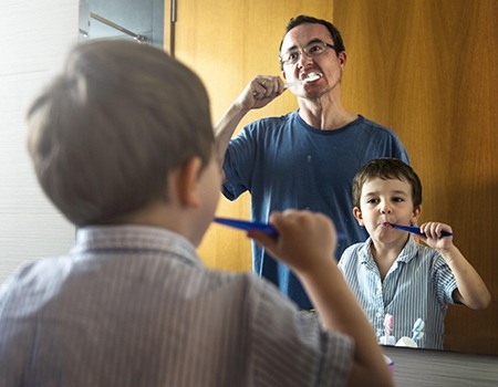 A father and son brushing their teeth together