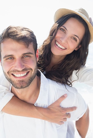 young couple smiling on the beach with veneers in Azle