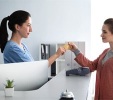 Woman using card to pay for dental treatment