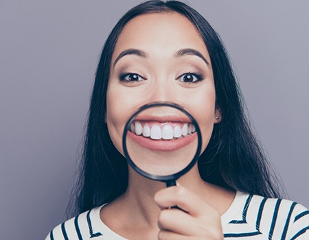 person holding a magnifying glass up to their smile