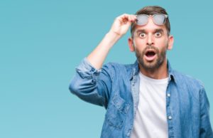 Man holding up his sunglasses, wearing shocked expression on face