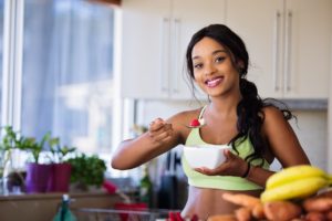 Young woman eating a bowl of fruit