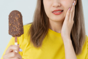 Woman rubbing her jaw after trying to eat ice cream