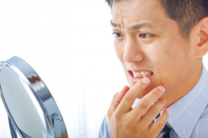 Man nervously looking in mirror at his chipped tooth